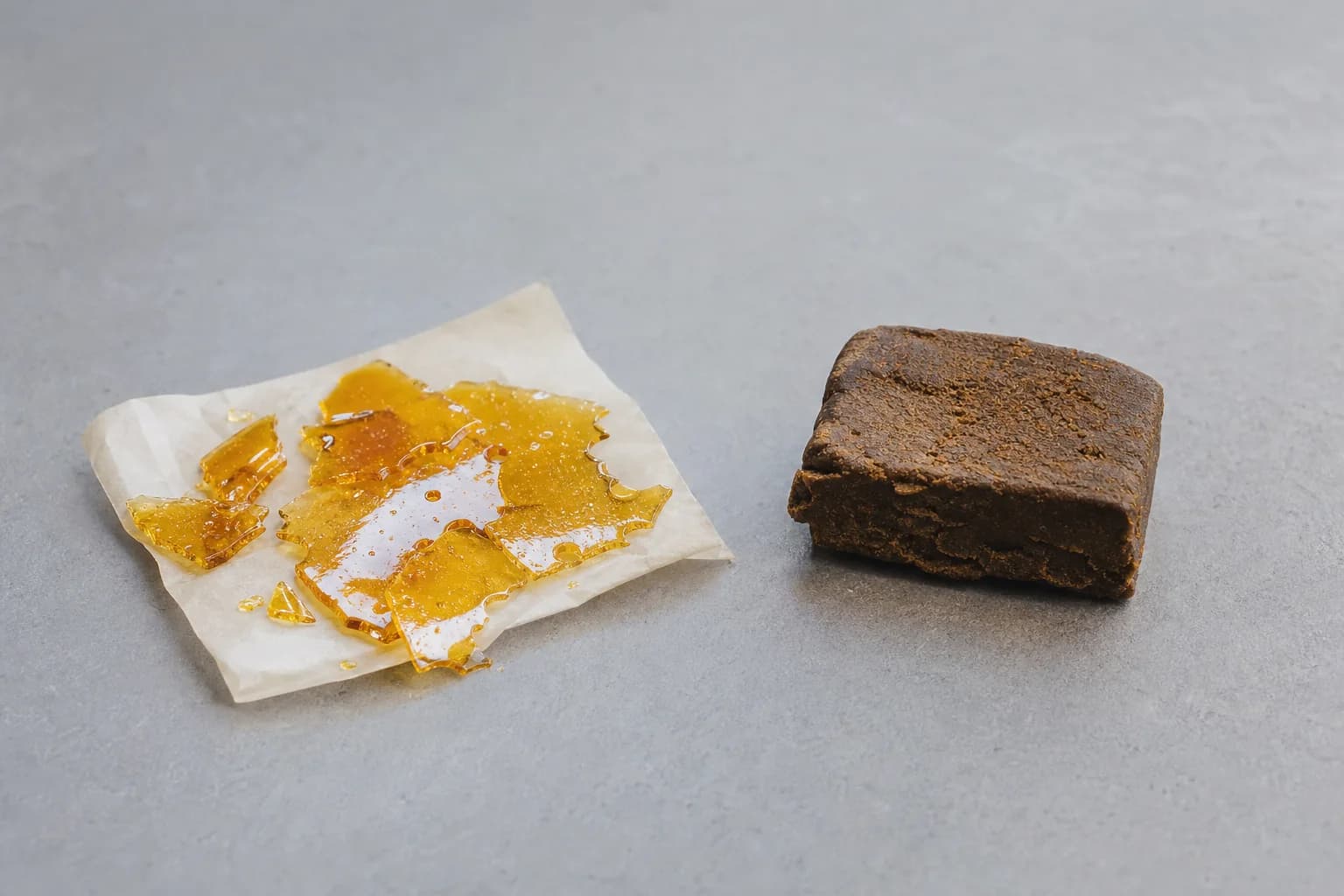 Amber glass-like shatter slab beside a dark brown pressed hash block